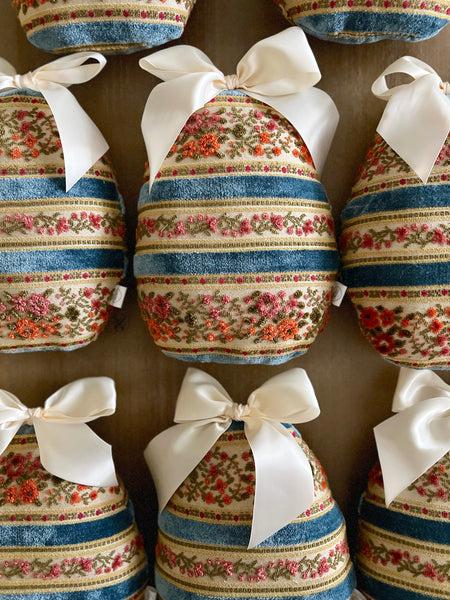Decorative Easter eggs with floral patterns and white bows on a wooden surface.