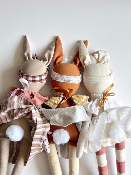 Three dolls with bunny ears and dresses on a white background