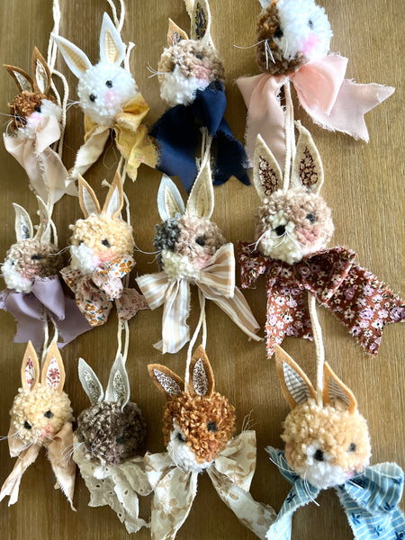 Decorative bunny ornaments with various colors and textures on a wooden surface.