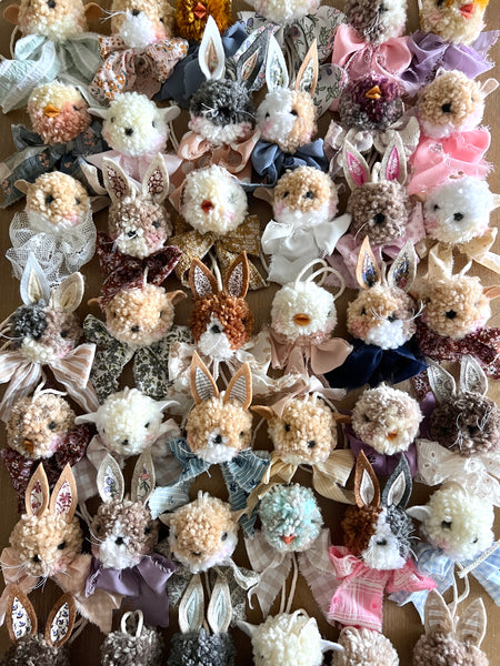 Collection of decorative bunny figurines with various colors and accessories on a wooden surface.