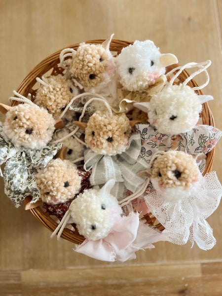 Decorative sheep figurines with lace details in a woven basket on a wooden surface.