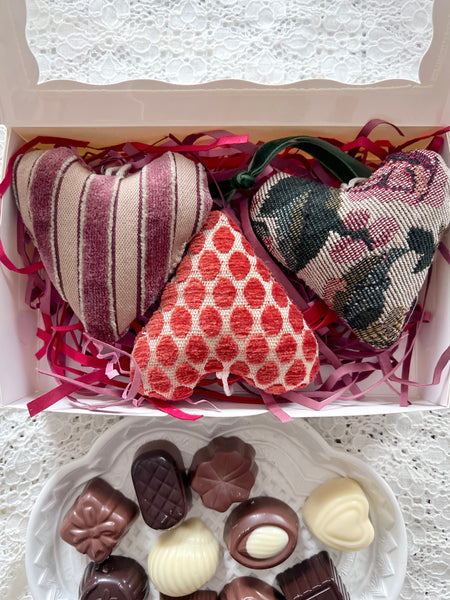 Fabric heart ornaments in open box with chocolates.
