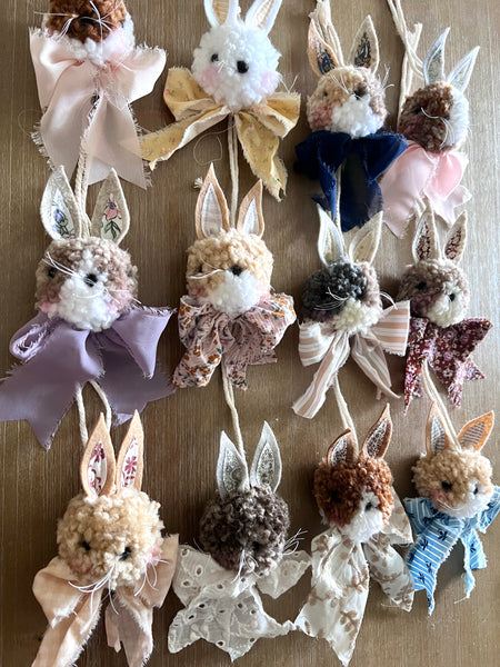 Collection of decorative bunny ornaments with various outfits on a wooden surface