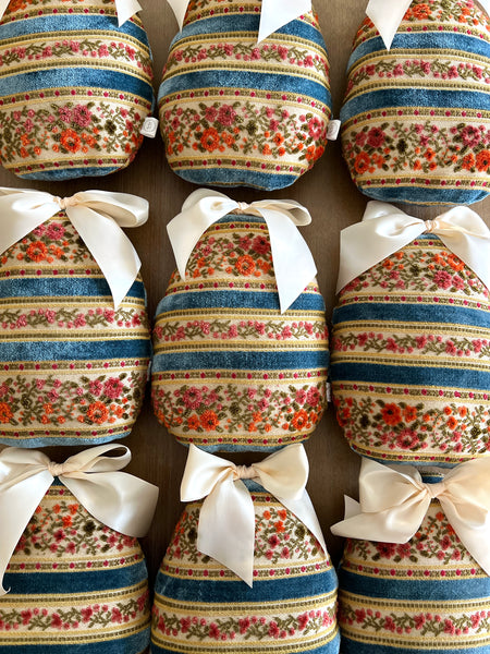 Decorative pillows with floral and striped patterns and white ribbons on a brown background