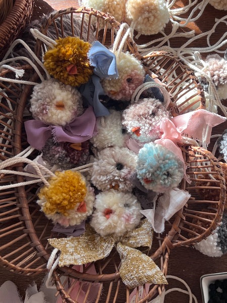 Decorative items including fluffy pom-poms and small plush toys in a wicker basket.