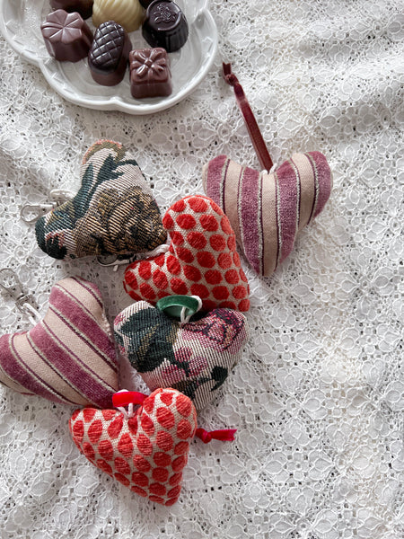 Fabric hearts on a lace tablecloth with a small plate of chocolates.