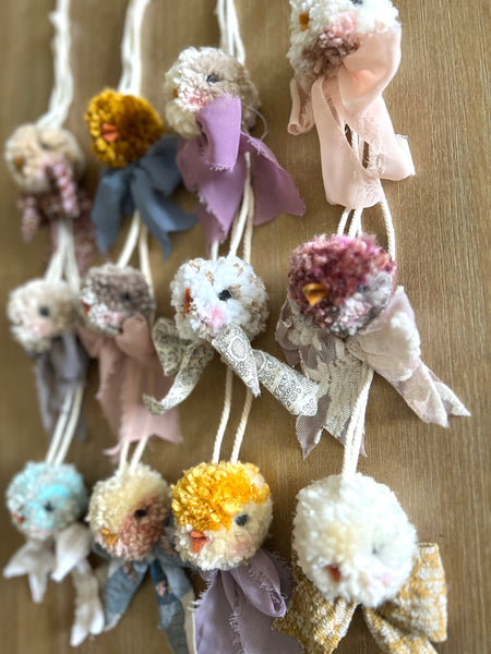 Decorative items resembling small creatures with colorful hair bows on a wooden surface