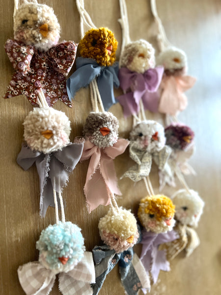 Decorative items resembling birds with colorful bows on a wooden surface