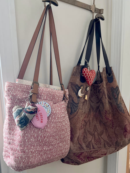 Two handbags hanging on a hook with decorative charms.