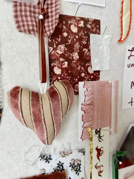 Heart-shaped fabric pillow on a surface with various fabric swatches and patterns.
