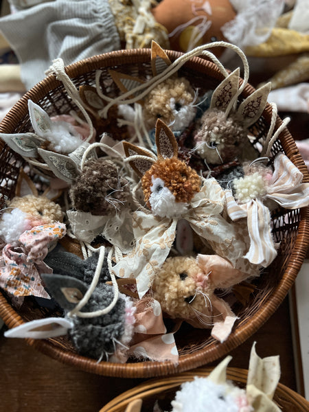 Basket filled with small decorative rabbit poms on a wooden table